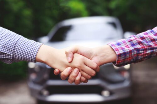 Deux personnes qui se serrent la main après achat d'une voiture d'occasion